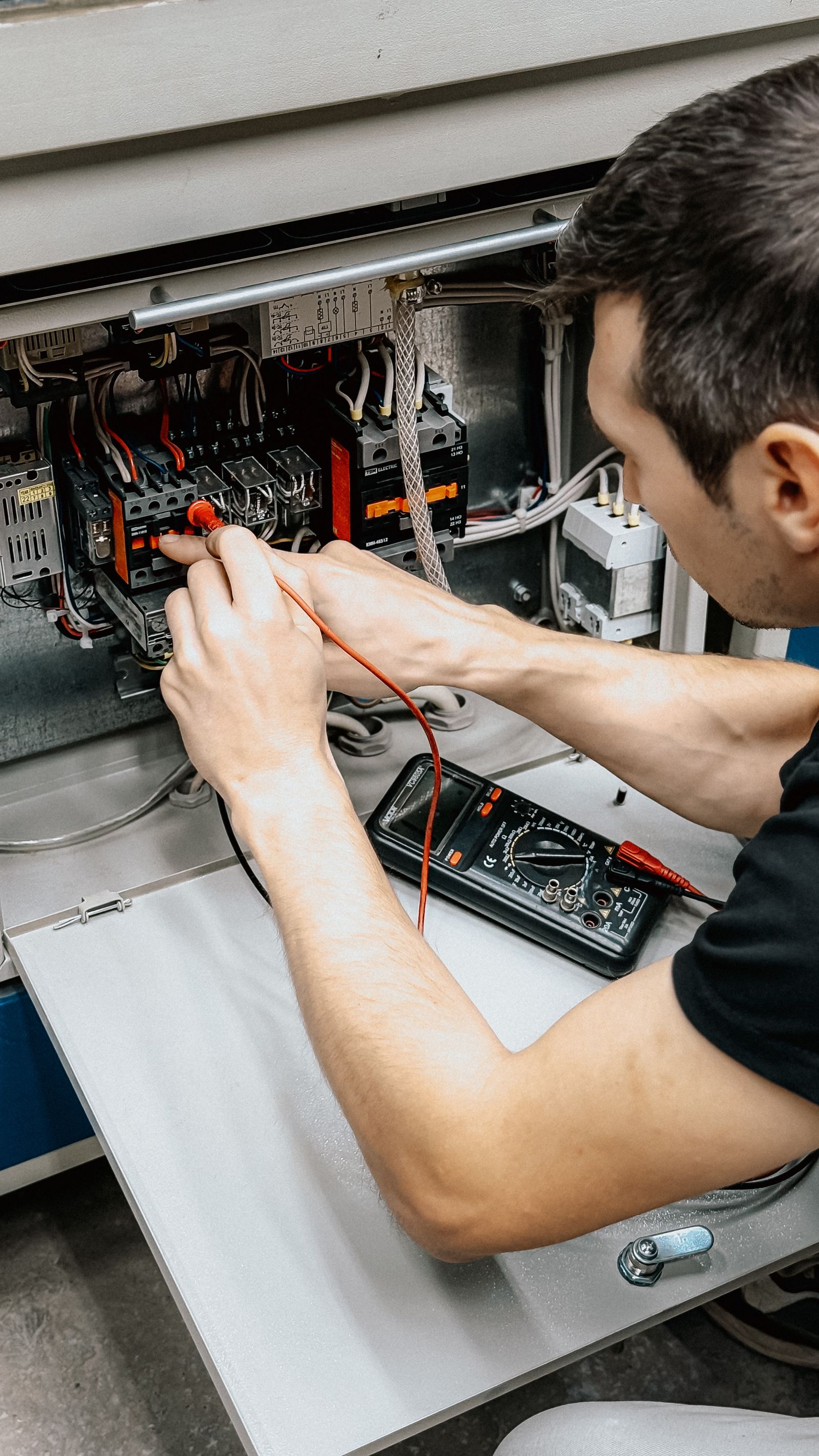 Electrician diagnosing an electrical panel with a multimeter